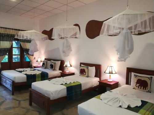 a room with three beds and two lamps at The Nature Park Villa in Sigiriya