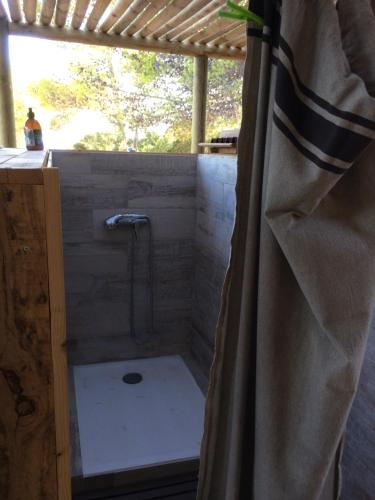 une salle de bain avec une douche avec un rideau de douche dans l'établissement Tente Lodge Bord de Mer, à Coti-Chiavari