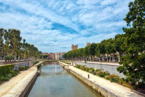 a river in a city with a bridge at Zenitude Hôtel-Résidences Narbonne Centre in Narbonne