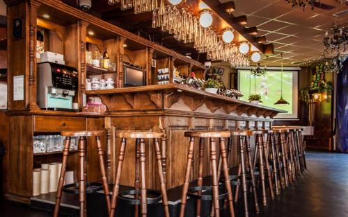 un bar con taburetes de madera en un restaurante en Rumpenerhof, en Brunssum