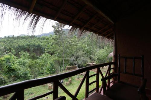 a room with a balcony with a view of a forest at Deshadan Eco Valley Resort - An Eco friendly Mud House in Kanthalloor