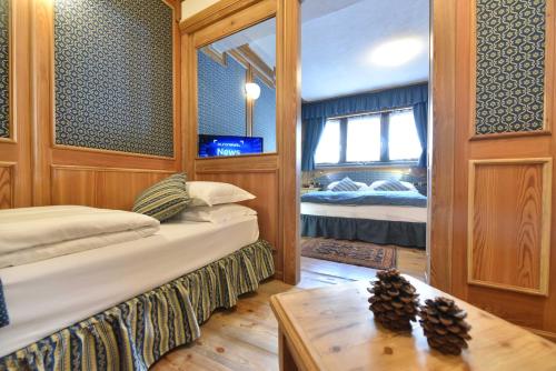 a room with two beds and a table and a mirror at Chambres Mont Cervin in Breuil-Cervinia