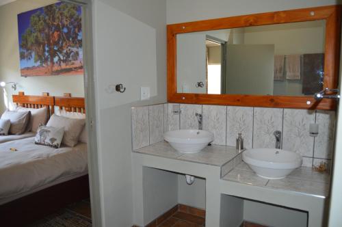 a bathroom with two sinks and a mirror and a bed at Kamaku Guesthouse in Otjiwarongo