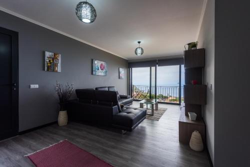 a living room with a couch and a chair and a balcony at Casa do Louro in Arco da Calheta