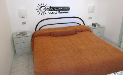 a bed with an orange comforter in a room at Appartamenti Baia Verde Gallipoli di Carlino Tourist in Gallipoli