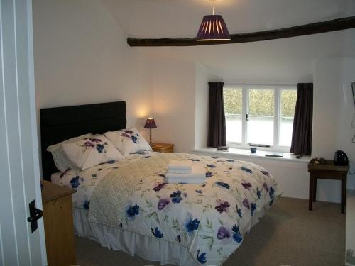 Middletown Farmhouse B&B في أوكهامبتون: غرفة نوم مع سرير مع لحاف من الزهور ونافذة
