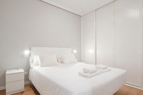 a white bedroom with a large white bed with towels on it at Estudios 8 in Madrid