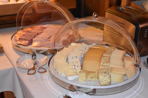 a tray of cheese and meats on a table with scissors at Hotel Gletschergarten in Grindelwald
