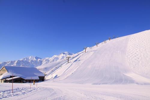 a snow covered ski slope with a ski lodge on it at Hotel Hakuba in Hakuba