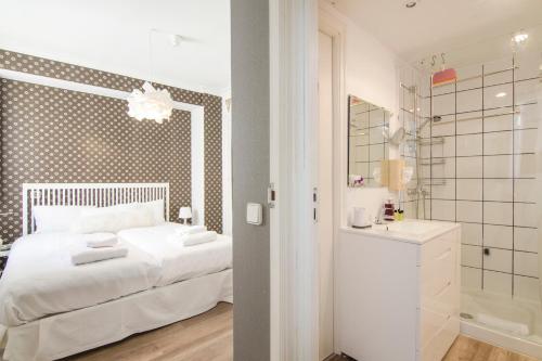 1 dormitorio con cama blanca y baño en Alcala 99, en Madrid