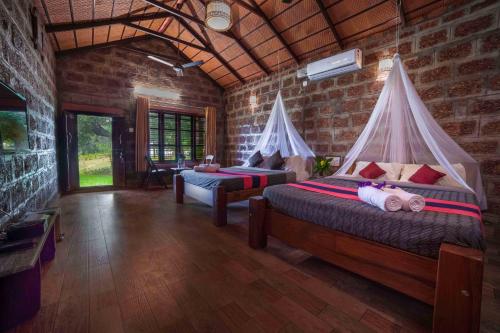 a bedroom with two beds in a room with brick walls at The Copper Edge in Kodlipet