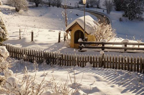 a small house covered in snow next to a fence at Chalet Cogolara in Colfosco