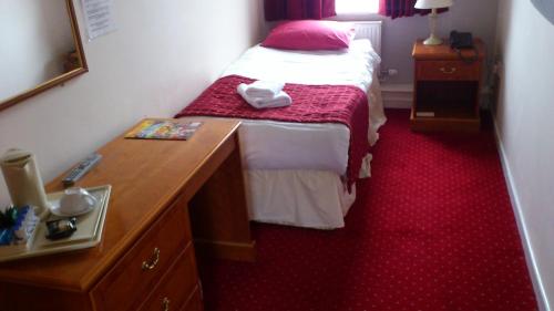 a small bedroom with a bed and a wooden dresser at The Griffin Hotel in Attleborough