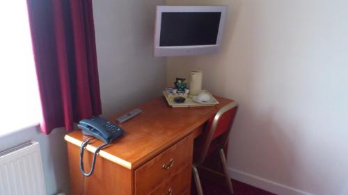 a room with a desk with a telephone and a television at The Griffin Hotel in Attleborough
