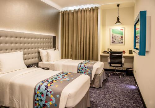 Un ou plusieurs lits dans un hébergement de l'établissement Fairway Colombo - Sri Lanka's First Hotel With Robot Technology