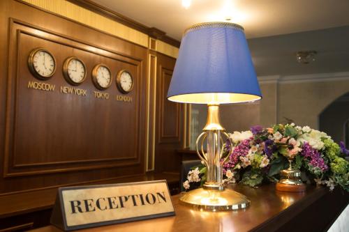a lamp on a table with a sign that says reception at MFK Gornyi Hotel and Congress Centre in Saint Petersburg