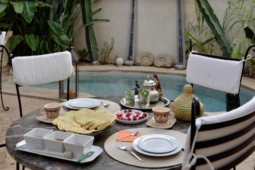 a table with food on it next to a swimming pool at Riad les Ammonites and Spa in Marrakech
