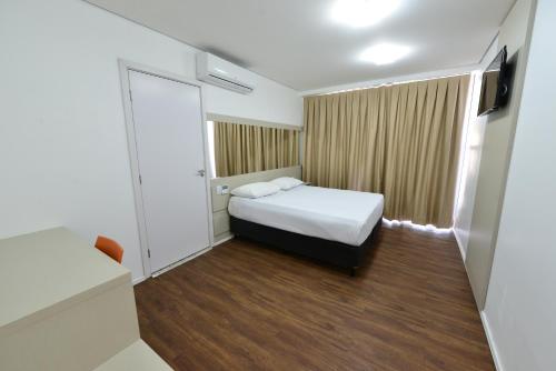 a small room with a bed and a television at Hotel Panorama Economic in Ipatinga