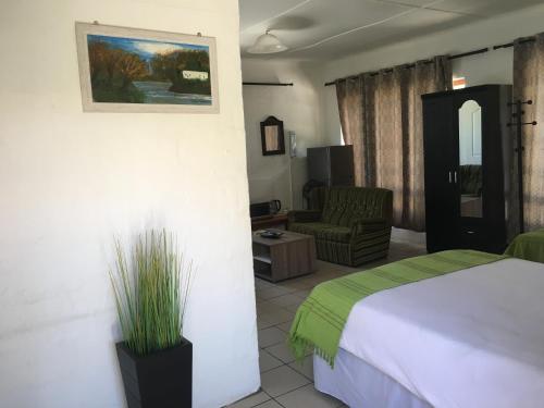 a hotel room with a bed and a chair at Rest Assured Guest House & Conference Kokstad in Kokstad