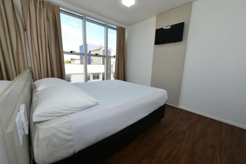 a bedroom with a white bed and a large window at Hotel Panorama Economic in Ipatinga