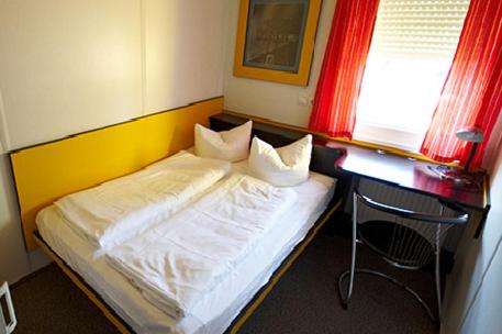 Bett in einem Zimmer mit einem Schreibtisch und einem Bett der Marke sidx sidx sidx. in der Unterkunft Motel Pelikan in Dettelbach