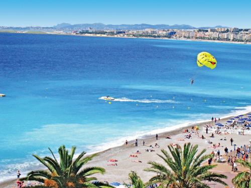 a group of people on a beach flying kites at Hôtel Le Royal Promenade des Anglais in Nice