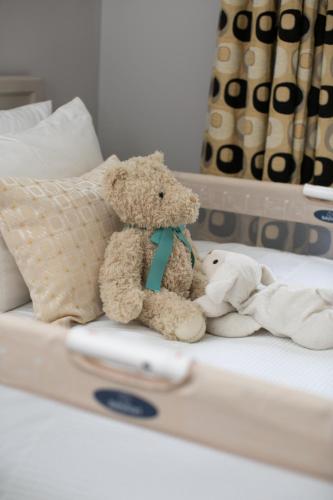 a teddy bear and a stuffed dog sitting on a bed at Cathedral View Apartments in Longford