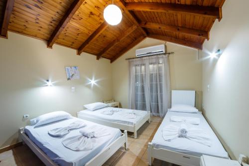 two beds in a room with wooden ceilings at Zante Bay Studios in Laganas