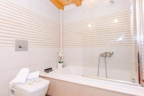 a white bathroom with a tub and a toilet at Mon Emvasia Margarites Villas in Margarítai