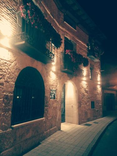 an alley with a building with a balcony and lights at Hotel Puerta del Arco in Tudela de Duero