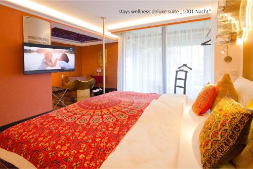 a bedroom with a bed with a tv on the wall at PLAZA INN stays design Dortmund in Dortmund