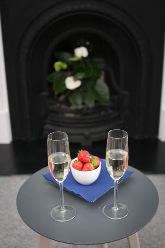 two glasses of wine on a table with a bowl of strawberries at Cathedral View Apartments in Longford
