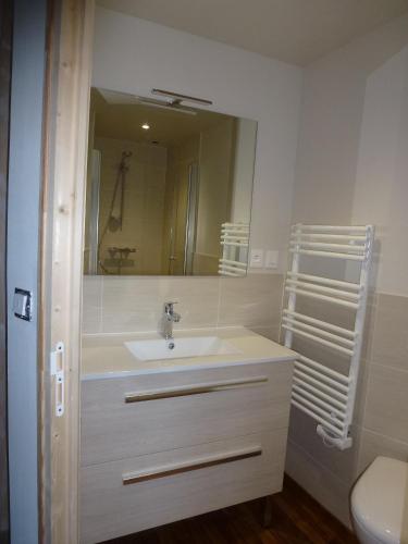 une salle de bain avec un lavabo et un miroir dans l'établissement Le Petit Clos, à Agon-Coutainville