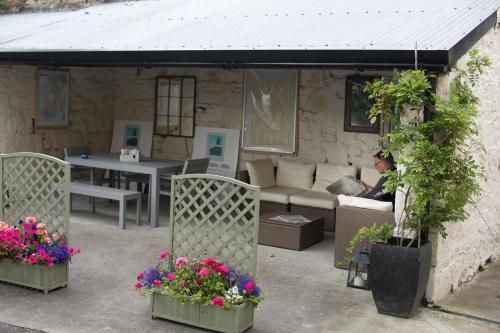 a woman sitting on a couch in a patio with flowers at Cathedral View Apartments in Longford