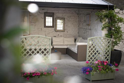 a patio with a couch and two chairs and flowers at Cathedral View Apartments in Longford