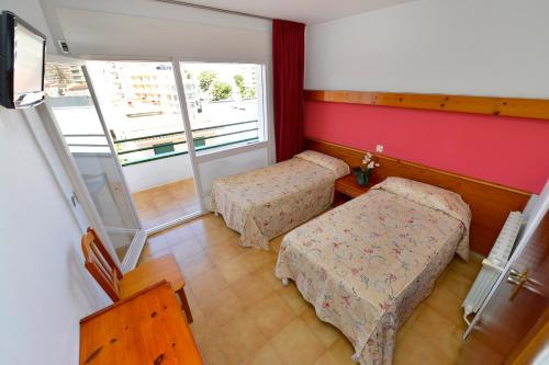 Habitación pequeña con 2 camas y ventana en Hostal Magnolia, en Lloret de Mar