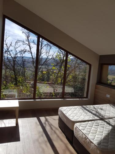 a bedroom with a bed and a large window at Mihaylova kushta in Lyubosh