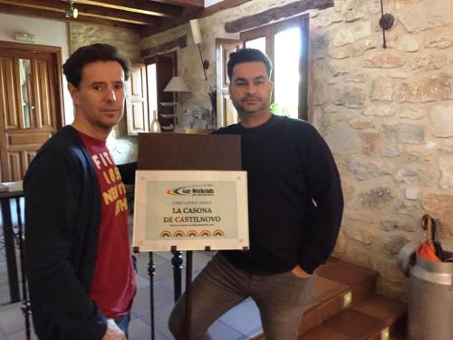 two men holding a box with a sign on it at La Casona de Castilnovo - Gay Men Only in Valdesaz