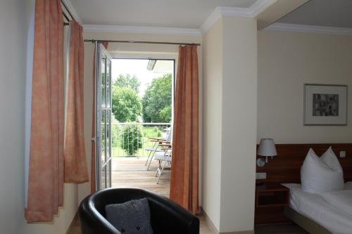 a room with a bed and a chair and a balcony at Hotel Villa Passion in Malchow