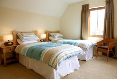 a bedroom with two beds and a window at Ardnagashel Woods in Bantry