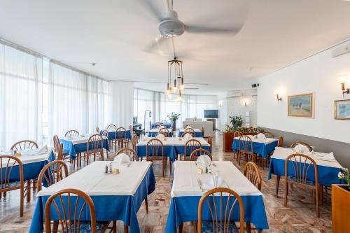 un comedor con mesas y sillas azules en Hotel Helvetia, en Grado