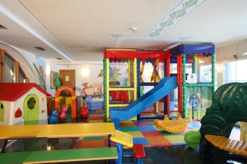 a play room with a slide and a playground at Alexander Hotel Alpine Wellness Dolomites in Molveno