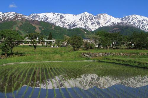 a mountain range with a reflection in a body of water at Hotel Hakuba in Hakuba