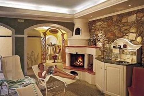 a woman sitting in a chair in a living room with a fireplace at Hotel Post in Großkirchheim