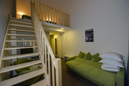 a living room with a green couch and a staircase at Hotel Posada Vidraru in Căpăţîneni-Ungureni