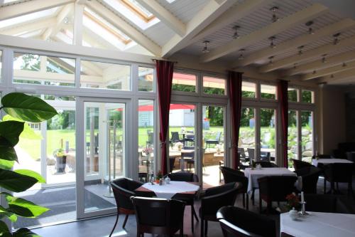 a dining room with tables and chairs and windows at Hotel Villa Passion in Malchow