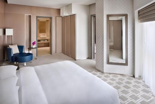 a bedroom with a white bed and a blue chair at Hyatt Regency Creek Heights Residences in Dubai