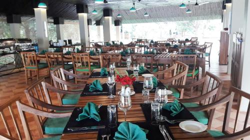 a restaurant with a long wooden table with green napkins at Rangiri Dambulla Resort in Dambulla
