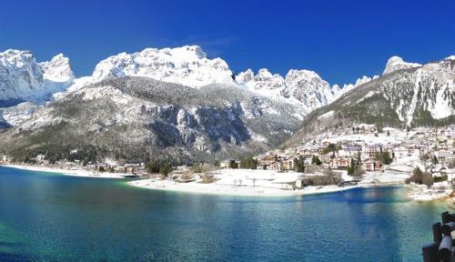 a large body of water with snow covered mountains at Alexander Hotel Alpine Wellness Dolomites in Molveno