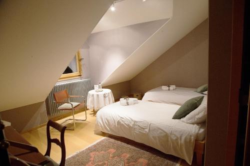 een slaapkamer op zolder met 2 bedden en een tafel bij Le Manoir in Chaumont